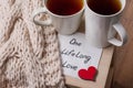One long life of love is an abstract symbolic image. Couple of cups, background warm scarf, in home interior, napkin with text