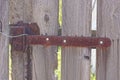 One long rusty brown door hinge on gray wooden fence Royalty Free Stock Photo