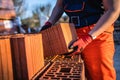 One man construction worker taking and carry or hold clay orange hollow blocks ar warehouse or construction site in sunny summer Royalty Free Stock Photo