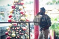 One man doing phone call inside a commercial mall center in christmas december season with holiday tree decorated in backgorund. Royalty Free Stock Photo