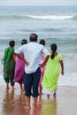 One man and four women, barefooted, gaze towards the rough sea