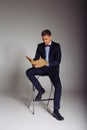 a man, a guy in a blue suit, sits on a chair and reads an old book, the concept of knowledge, study, science, business, everything Royalty Free Stock Photo