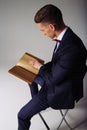 A man, a guy in a blue suit, sits on a chair and reads an old book, the concept of knowledge, study, science, business, everything Royalty Free Stock Photo