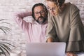 One man having relax stretching shoulder at office while woman colleagues use his computer. Small business team couple concept Royalty Free Stock Photo