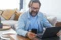 One man at home using mobile phone and laptop on the table. Concept of online small business and smart working people lifestyle. Royalty Free Stock Photo