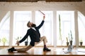 One man, office clerk wearing business style clothes having fun, doing yoga on wooden table in modern office at work