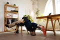 One man, office clerk wearing business style clothes having fun, doing yoga on wooden table in modern office at work