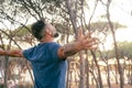 One man outstretching arms in front of a high trees forest and sunset sunlight. Concept of environment and healthy lifestyle. Royalty Free Stock Photo