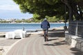 One man riding bike on the promenade by the beach, rear view