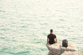 One man sit in back on rock by the sea with backpack Royalty Free Stock Photo