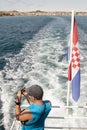 One man standing on a back of a ship taking photo on mobile phone and Croatian flag