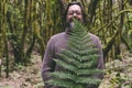 One man standing in the forest bush woods with big tropical green leaf leaves. Concept of natural lifestyle and environment