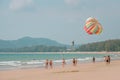 One man starting parasailing fly. People on a beach look at him up. Colorful parachute. Close up photo on clear blue sky. PHUKET Royalty Free Stock Photo