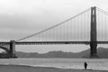 One man walks on the beach under the Golden Gate Bridge in San F Royalty Free Stock Photo