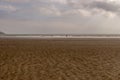 One man and a woman walking on sandy beach with a dog. Family enjoying the day. Kilbrittain, Killbrittain beach, Ireland