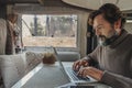 One man working on laptop computer inside camper van in alternative office and job lifestyle. Freedom in smart working people. Royalty Free Stock Photo