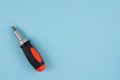 One manual screwdriver with rubber handle of black and orange color on blue background Royalty Free Stock Photo