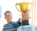 One of many more awards to come his way. an intelligent young boy proudly holding his academics trophy at home.