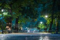 One of the many parks or streets in Krakow, Poland at night. Visible lamp poles, walkway and small fence