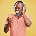 One mature african american man listening to music using wireless headphones while isolated against a yellow background Royalty Free Stock Photo