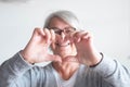 One mature woman or senior at home doing a heart with her hands and fingers - happy pensioner