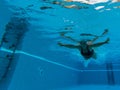 One mature woman or senior swimming alone in a swimming pool and training to be healthy and fitness - active female - under water
