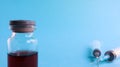 One medical glass bottle with red potion on a blue background and two medical disposable syringes with a needle. Medical concept