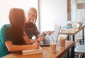 One-on-one meeting. Two young business women sitting at table in cafe. Girl shows colleague information on laptop screen Royalty Free Stock Photo