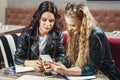 One-on-one meeting. Two young business women sitting at table in cafe. Girl shows colleague information on the smartphone screen. Royalty Free Stock Photo