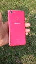 One men holding a oppo f5 mobile in her hend colour red