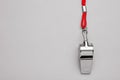 One metal whistle with red cord on light grey background, top view. Space for text Royalty Free Stock Photo