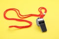 One metal whistle with red cord on yellow background Royalty Free Stock Photo
