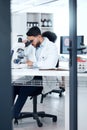 One mixed race scientist wearing safety goggles while analysing medical test samples with a microscope in a lab. Young