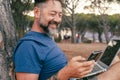 One modern adult man using and working on laptop at the park. Concept of smart working and freelance digital nomad small business Royalty Free Stock Photo