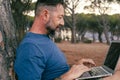 One modern adult man using and working on laptop at the park. Concept of smart working and freelance digital nomad small business Royalty Free Stock Photo