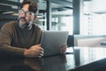 One modern man working on laptop at the desk in empty office or coworking space with light in background. Scared for security Royalty Free Stock Photo