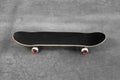 One modern skateboard with black griptape on ground outdoors Royalty Free Stock Photo