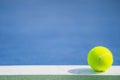 One new tennis ball on white line in blue and green hard court with light from right Royalty Free Stock Photo