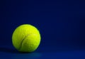 One new tennis balls on blue court with light from left, shadow and copy space on right Royalty Free Stock Photo