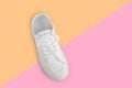 One new white female or teen sneaker isolated on trend yellow-pink background. White textile sneaker with rubber soles with tied Royalty Free Stock Photo