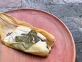 One Oaxacan tamales with hoja santa wrapped on the outside of the masa