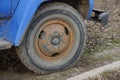 One old black big wheel in brown rust on a peanut truck is standing on the ground and grass Royalty Free Stock Photo