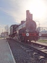 one old black iron steam locomotive with a green wagon stands on the rails of the railway Royalty Free Stock Photo