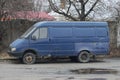 One old blue minibus car stands on a gray wet asphalt road