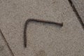 One old brown rusty bent iron nail lies on a gray stone pavement Royalty Free Stock Photo