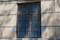 Old brown window behind bars on a gray concrete wall Royalty Free Stock Photo