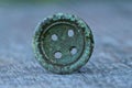 Old copper green button with holes on a gray table