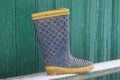 One old dirty yellow blue rubber boot stands on a wooden bench in white snow Royalty Free Stock Photo