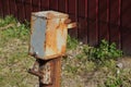 Old gray brown rusty metal box for electricity on a pole outside the fence Royalty Free Stock Photo