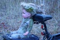 one old gray dirty doll toy sits on the trunk of a black bicycle Royalty Free Stock Photo